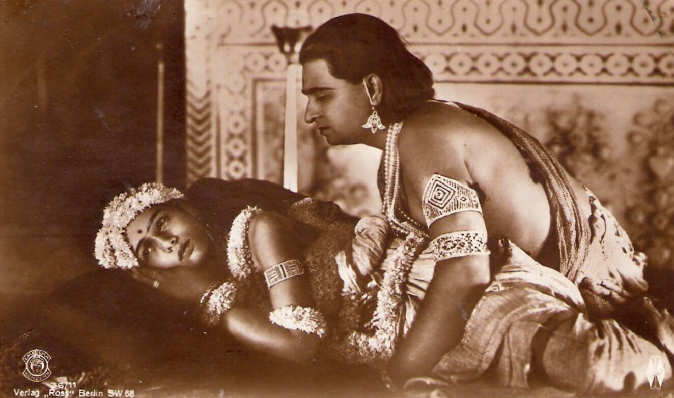 Sepia image of a two people. Woman is reclining and man is leaning over her.